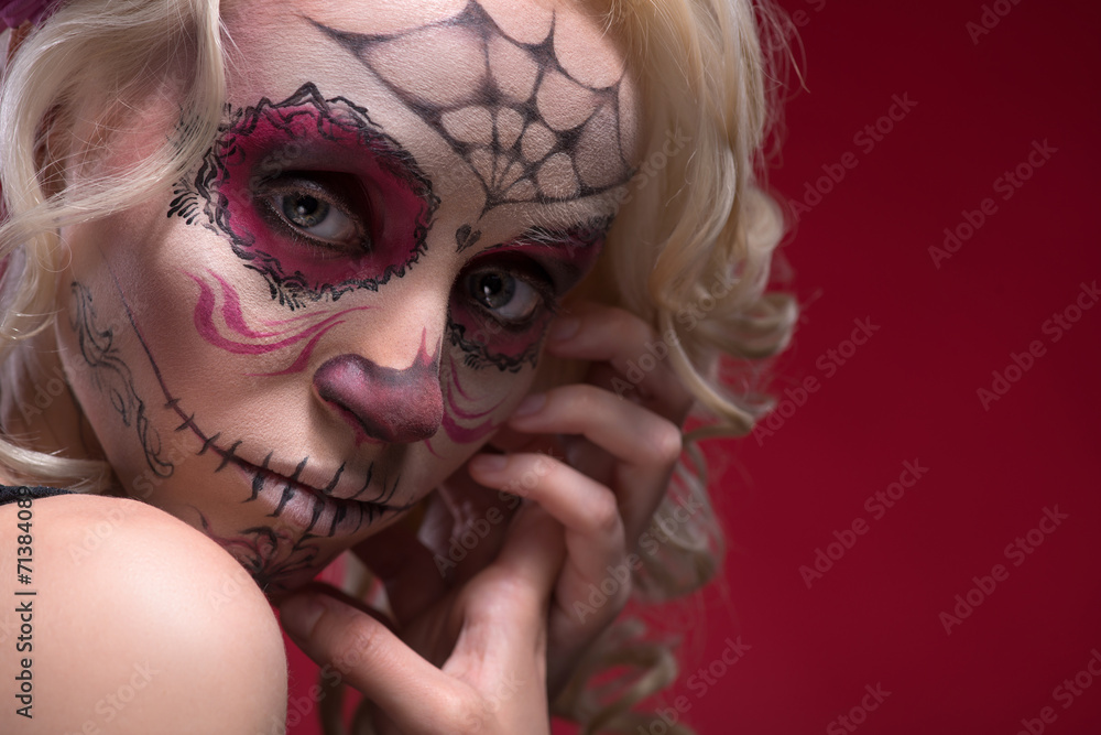 Portrait of young blond girl with Calaveras makeup and a rose fl