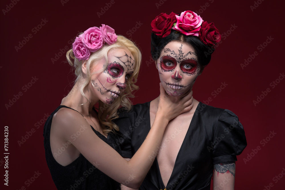 Portrait of two young girls in black dresses with Calaveras make