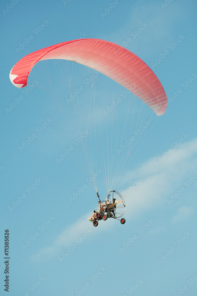 Extreme athletes paragliding in clear blue sky Extreme athletes paragliding in clear blue sky