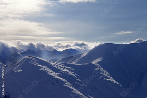 Snowy mountains in mist at sun evening