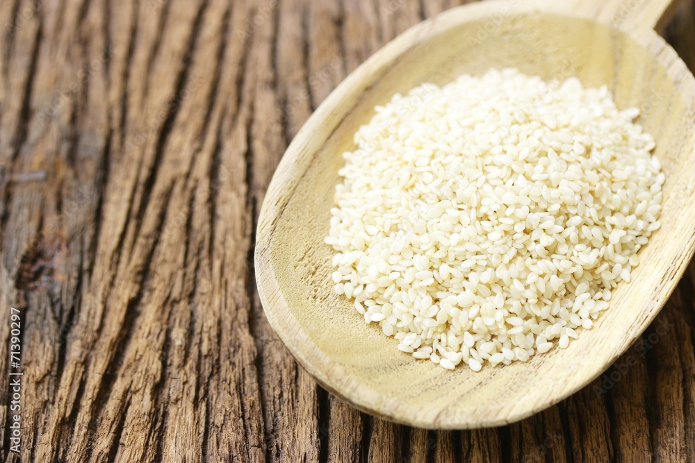 White Sesames in wooden spoon on wooden table White Sesames in wooden spoon on wooden table