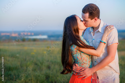 young beautiful couple on a cliff at sunset