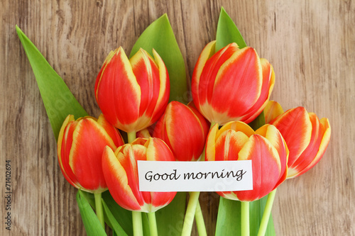 Good morning card with red and yellow tulips on wooden surface