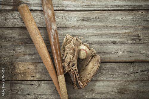 Old baseball with mitt and bats on rough wood
