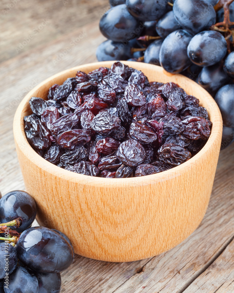 raisins in bowl and grapes on old wooden table raisins in bowl and grapes on old wooden table