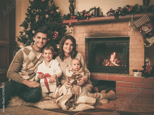 Family near fireplace in Christmas decorated house © Nejron Photo
