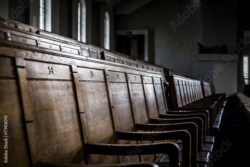 Rows of wooden pews in a closed down building