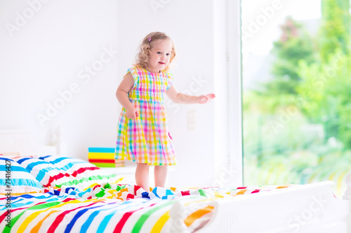 Little girl jumping on a bed