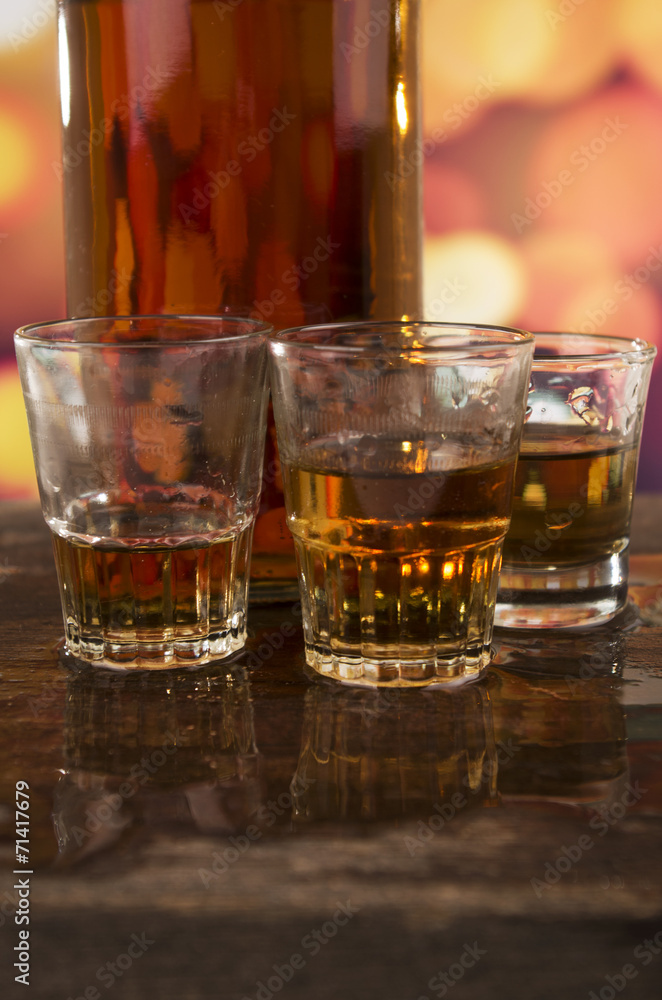 glass of rum whiskey over defocused lights background glass of rum whiskey over defocused lights background