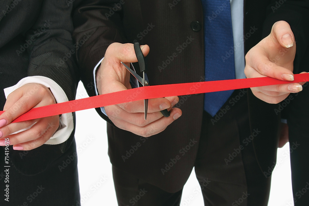 Business people cutting a red ribbon with a pair of scissors,