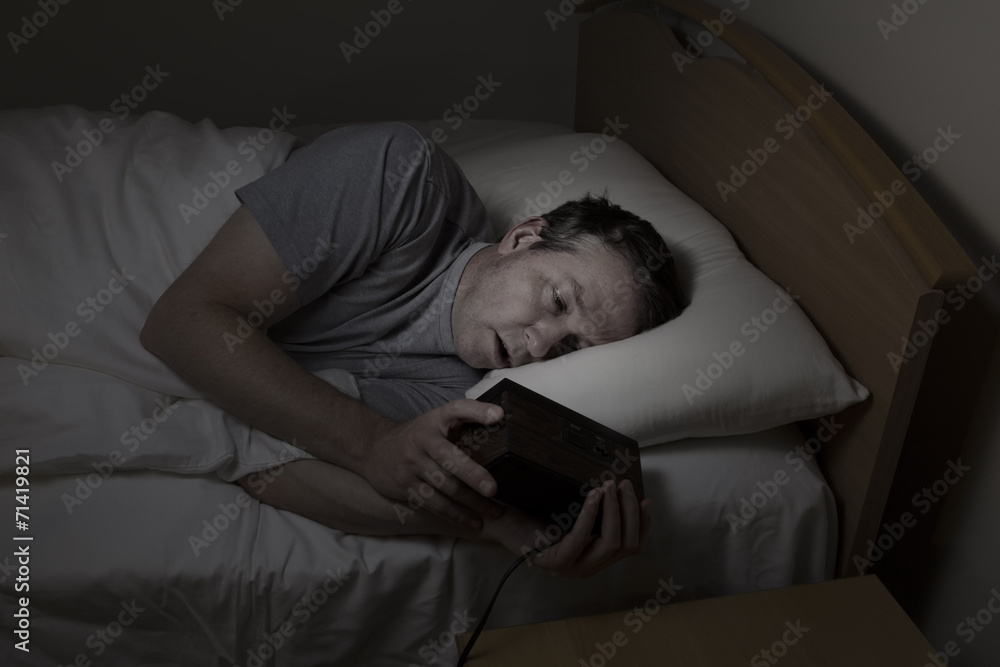 Mature Man checking time while trying to sleep Mature Man checking time while trying to sleep