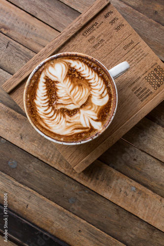 Cup of hot latte art coffee on wooden table