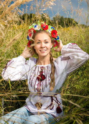 ukrainian girl in national clothes sitting on meadow