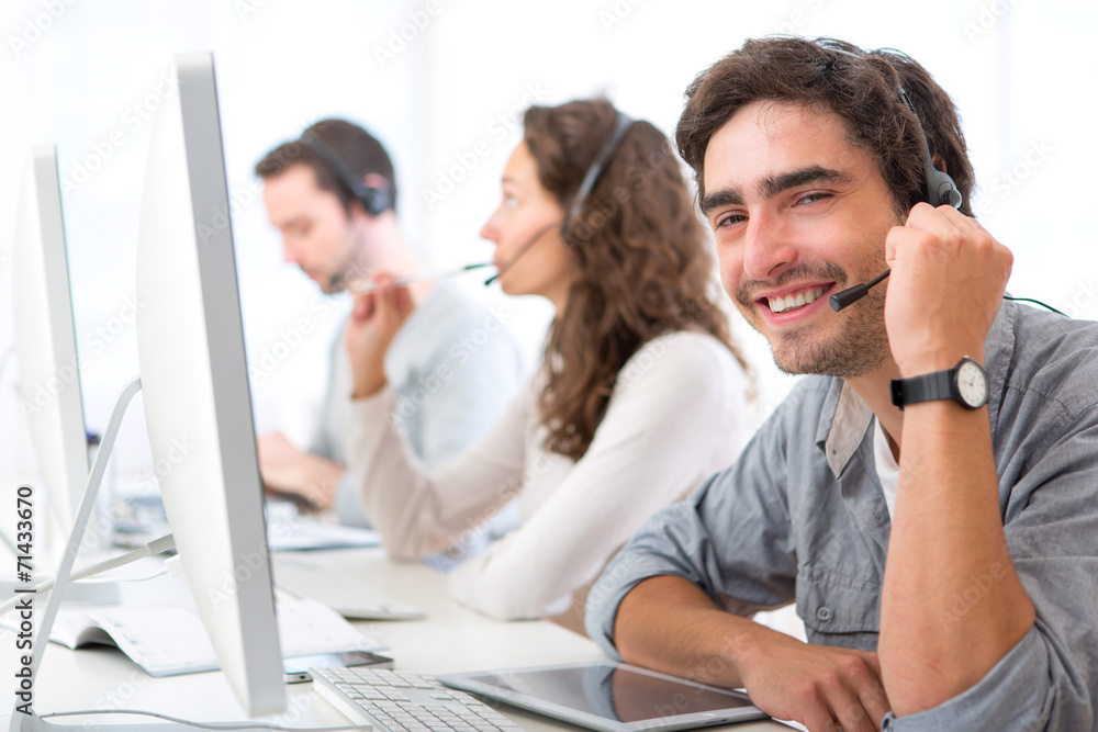 Fototapeta premium Young attractive man working in a call center