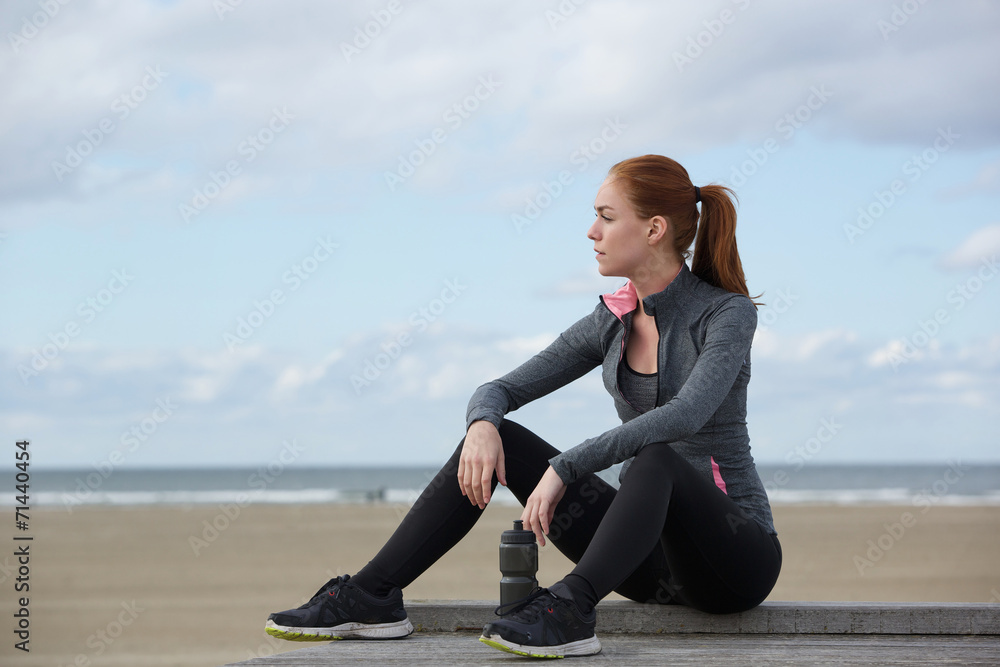 Attractive sports woman relaxing by the beach after workout