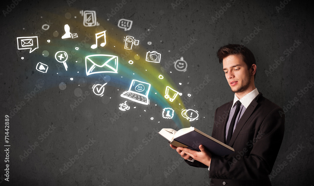 Young businessman reading a book with multimedia icons coming ou Young businessman reading a book with multimedia icons coming ou