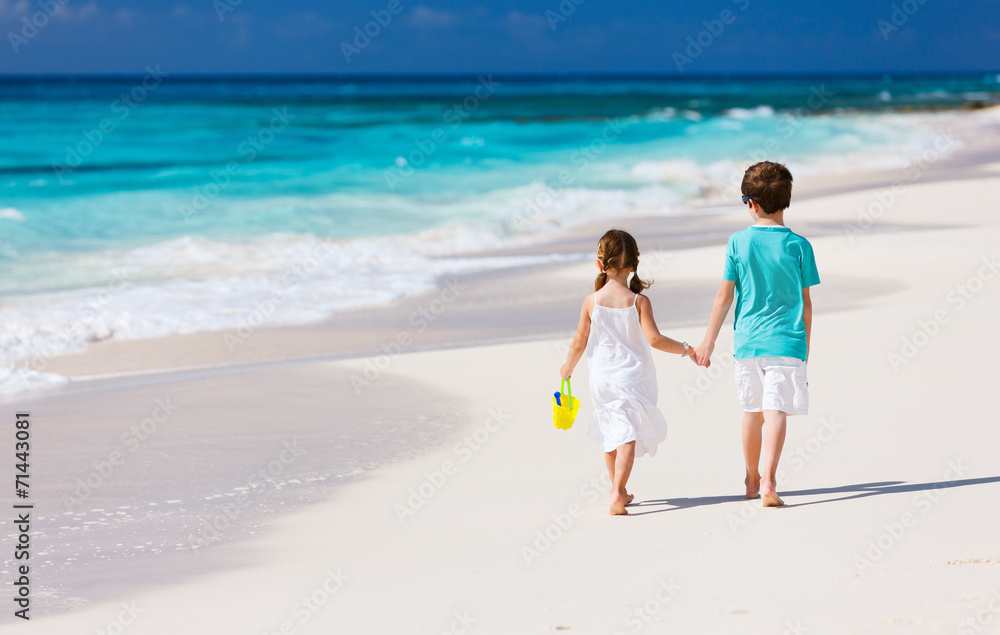 Two kids walking along a beach at Caribbean