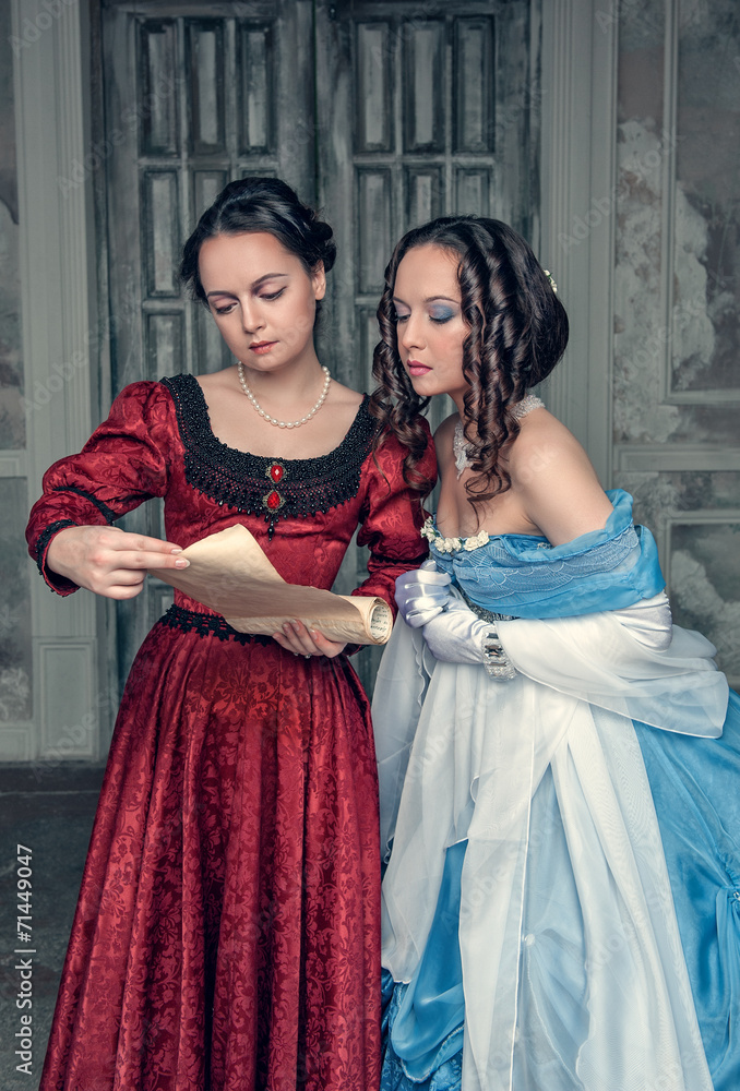 Beautiful girls in medieval dresses with scroll letter Beautiful girls in medieval dresses with scroll letter