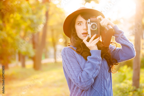 Brunette girl with camera in the park in sunset time
