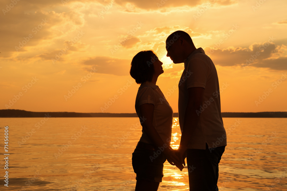 Young romantic couple look to each other during sunset on the be