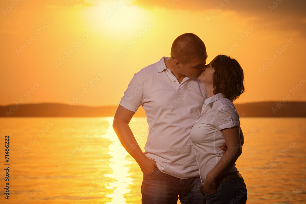 Young romantic couple look to each other during sunset on the be
