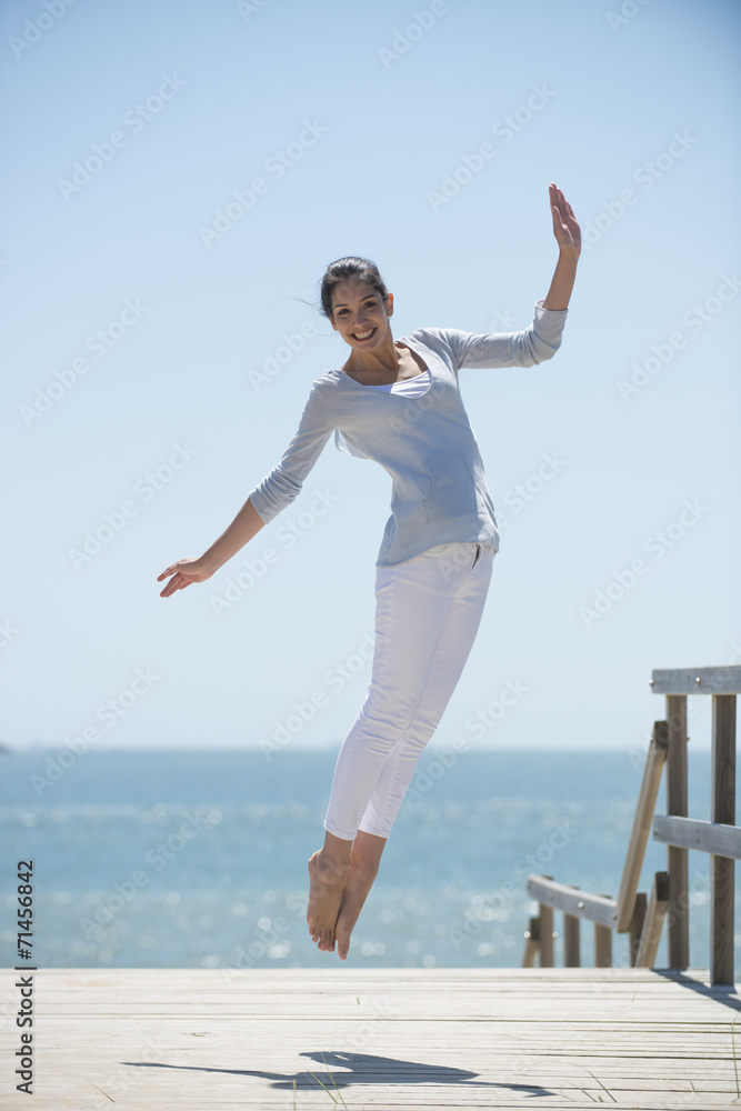 young woman full of energy jumping on a pontoon in front of the