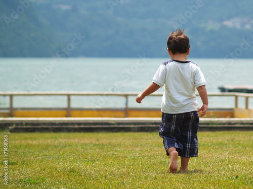 Photos child walking from behind barefoot on the shore of a lake