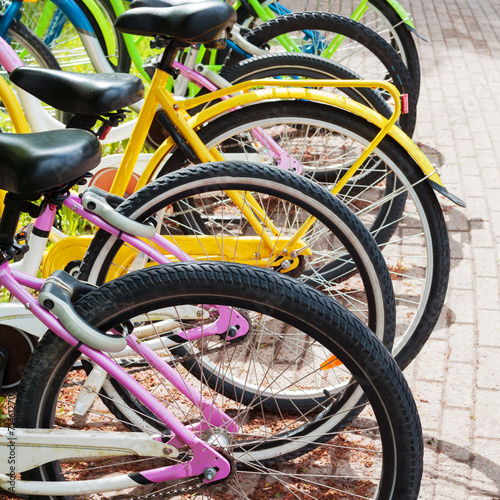 Colorful bicycles stand in row on a parking lot for rent