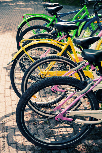 Colorful bicycles stand in row on a parking lot for rent, styliz