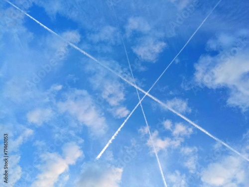 3 Kondensstreifen kreuzen sich am Himmel zu einem Dreieck. photo
