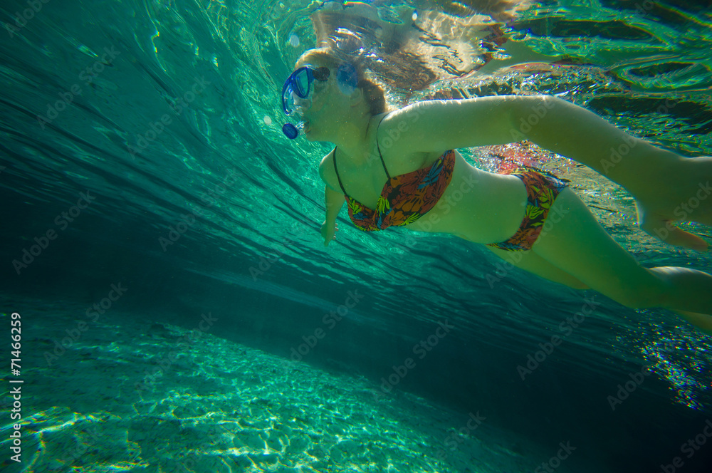 Young woman snorkeling in crystal clear laguna water on tropical