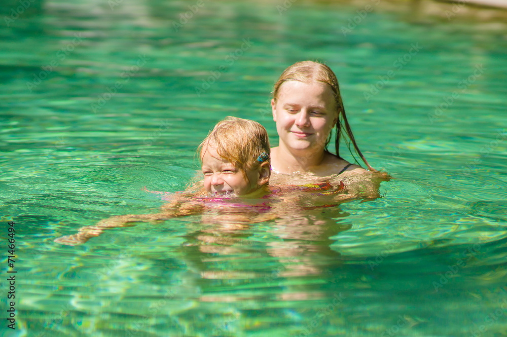 Young mother and daughter swimming in crystal clear laguna on tr