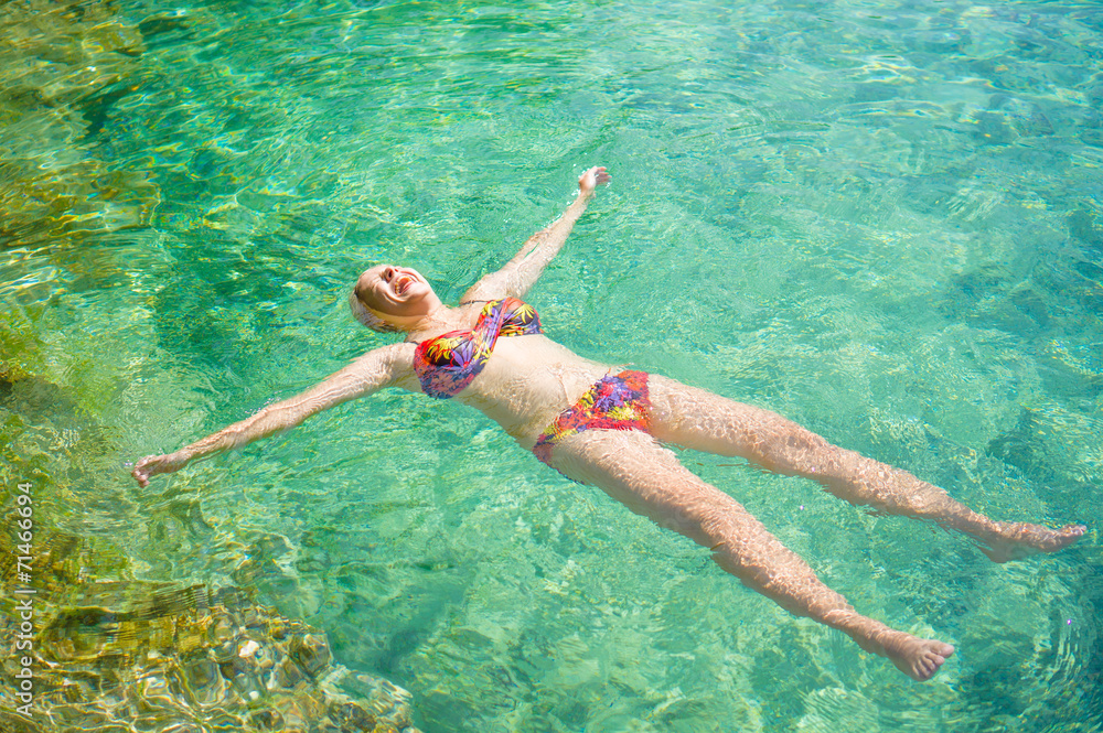 Young woman relax in crystal clear laguna on tropical island