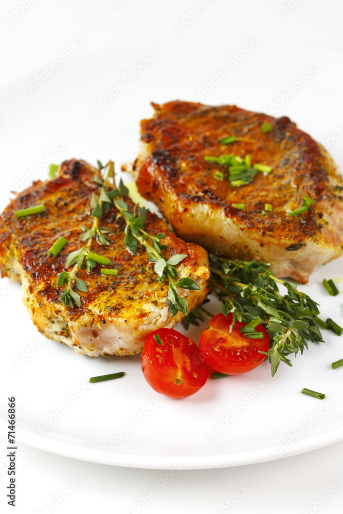 Fresh roasted pork steaks on white plate Fresh roasted pork steaks on white plate