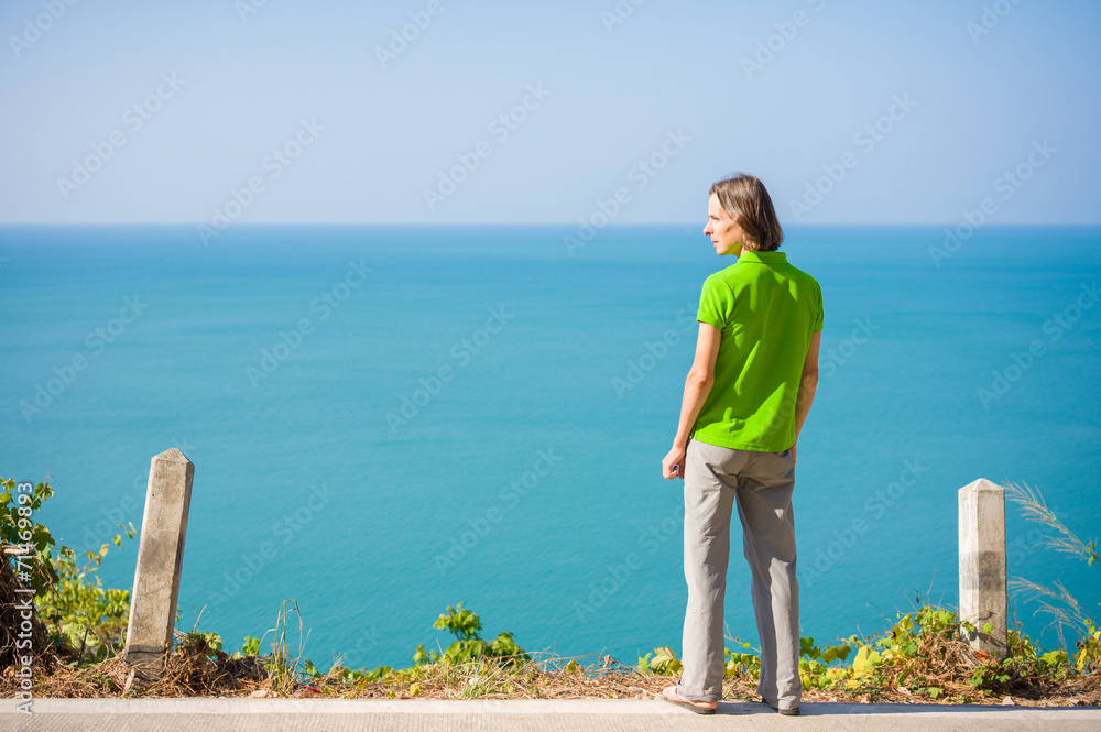 Young man stay on mountain road along tropical island beach and Young man stay on mountain road along tropical island beach and