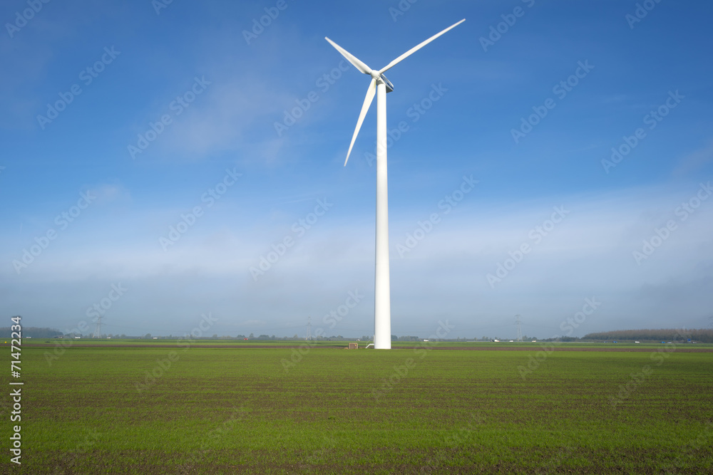 White wind turbine in a sunny meadow at fall White wind turbine in a sunny meadow at fall