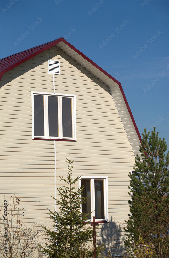 New built country house with red roof and beige siding