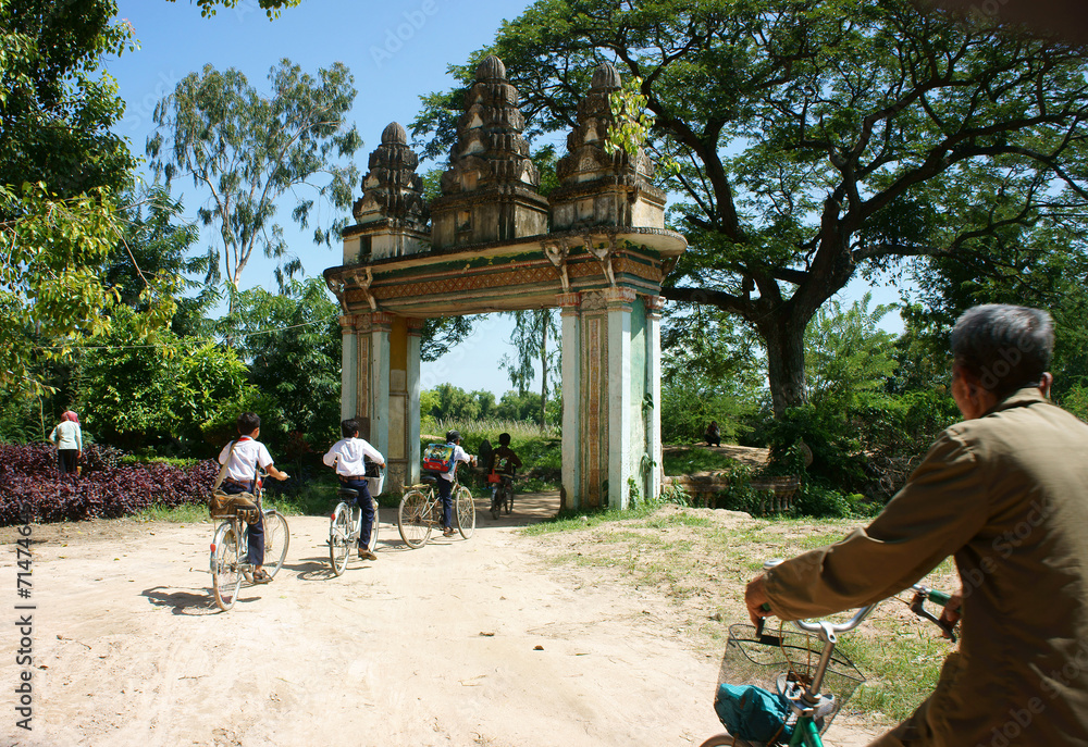 Group Asian kids, riding bike, Khmer village gate
