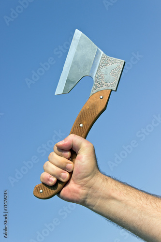 Old axe in hand over blue sky
