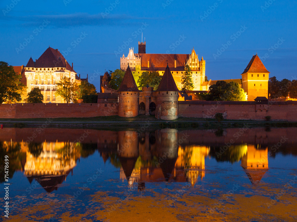 Malbork castle by night with reflection in Nogat river