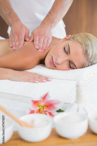 Woman receiving shoulder massage at spa center