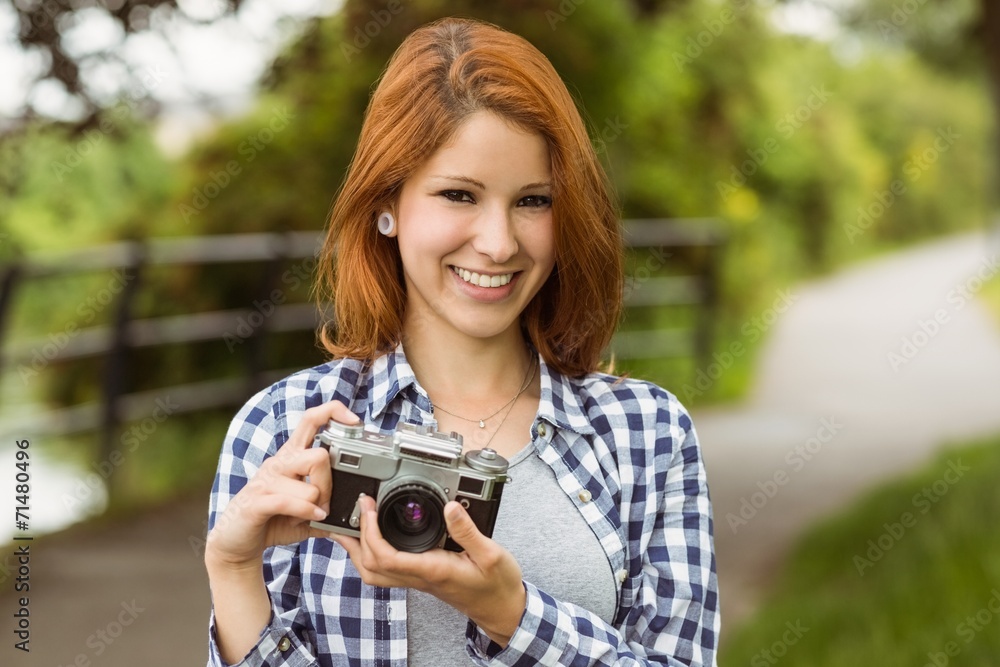 Smiling pretty redhead holding her camera