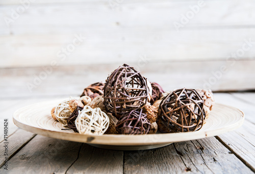Decorative twig spheres lay in wooden bowl on wooden table