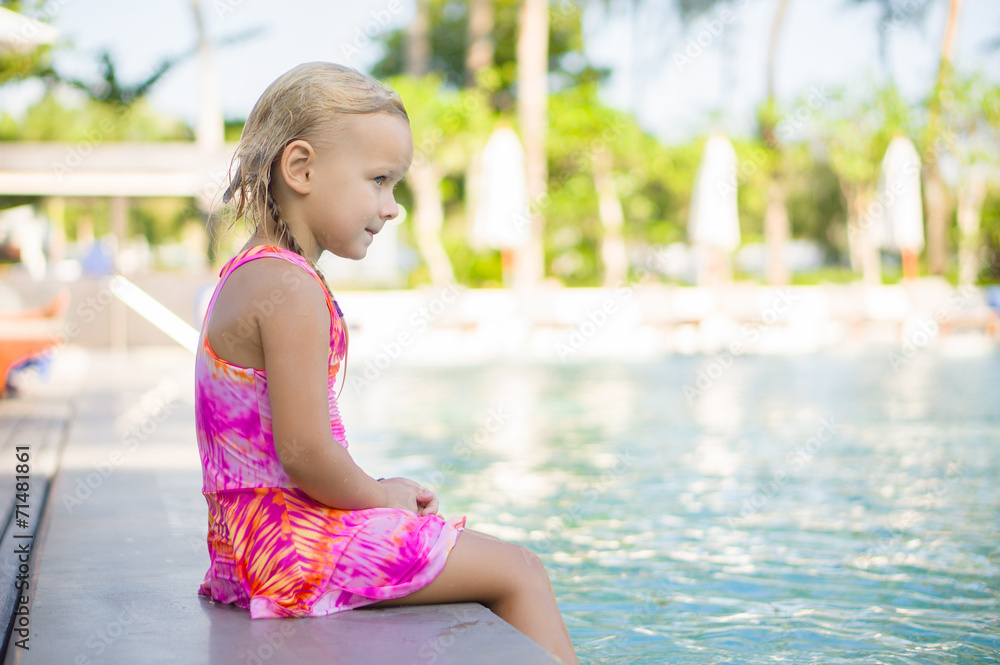 Naklejka premium Adorable girl seat on pool side at tropical beach with legs in