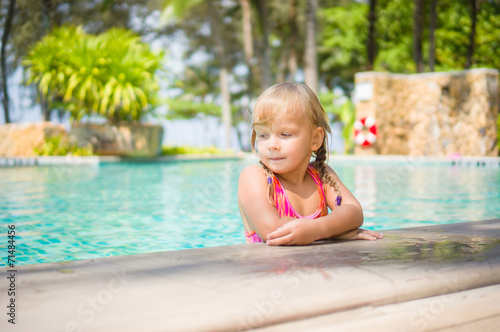 Adorable girl stay in water at side of swimming pool in tropical © Joshhh