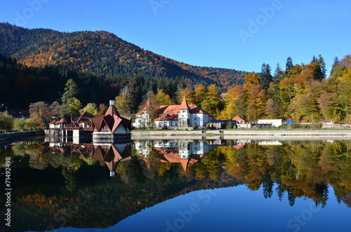 Beautiful fall landscape with a lake house reflected in Saint Ana lake in Tusnad photo