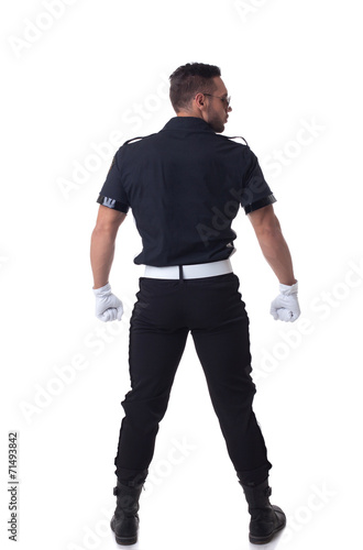 Fashionable muscular cop posing back to camera