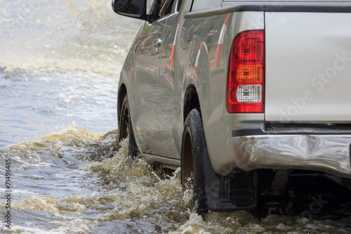 Car splashes through a large puddle on a flooded street