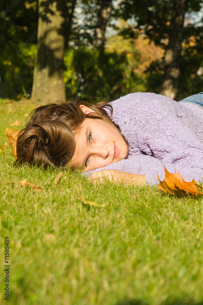 Cute little girl lies on a green lawn in autumn Cute little girl lies on a green lawn in autumn