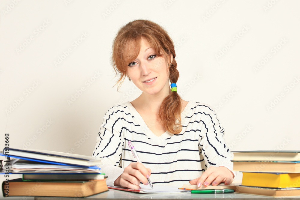 Charming girl sitting at table with books studying Charming girl sitting at table with books studying